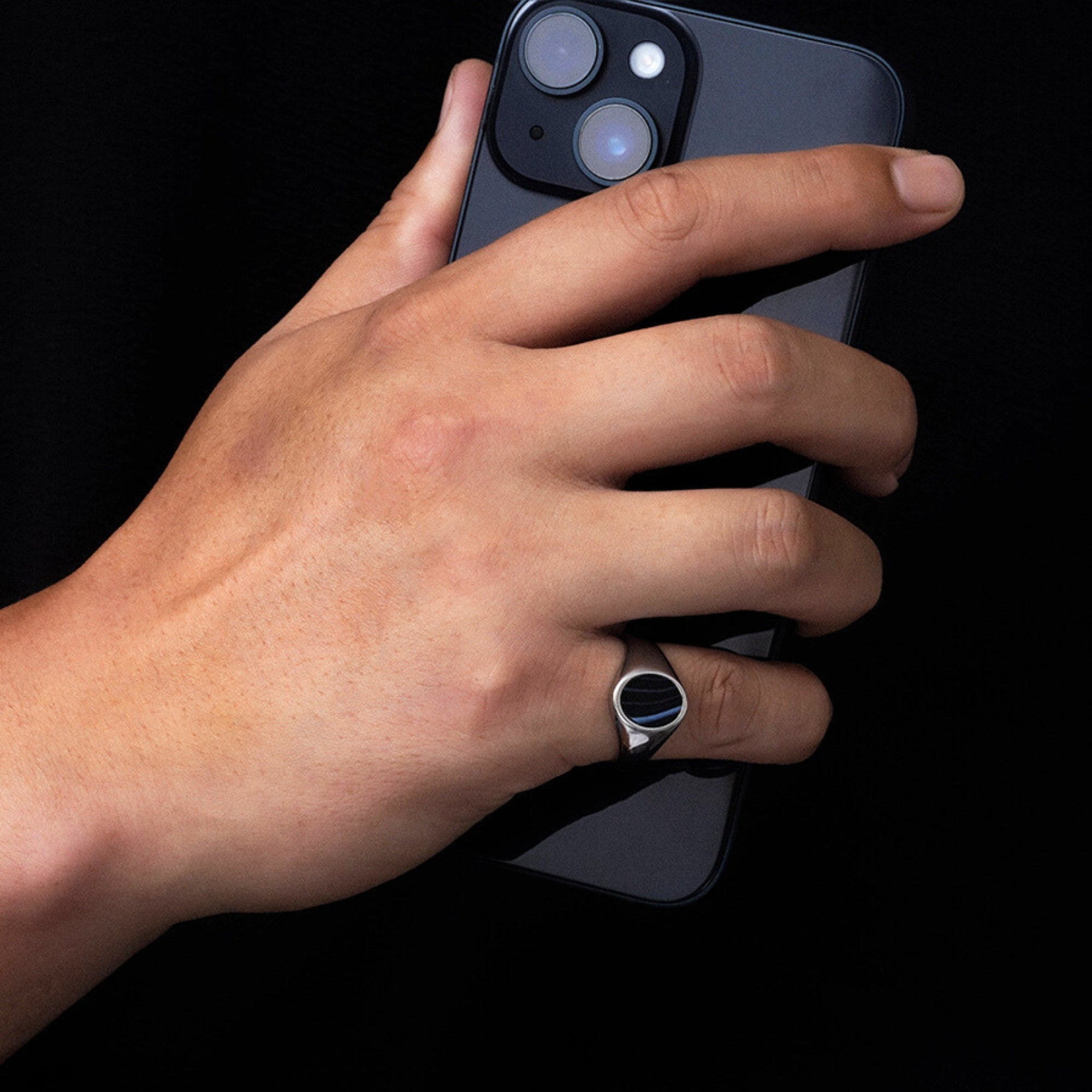 Hand holding a smartphone with a dark background