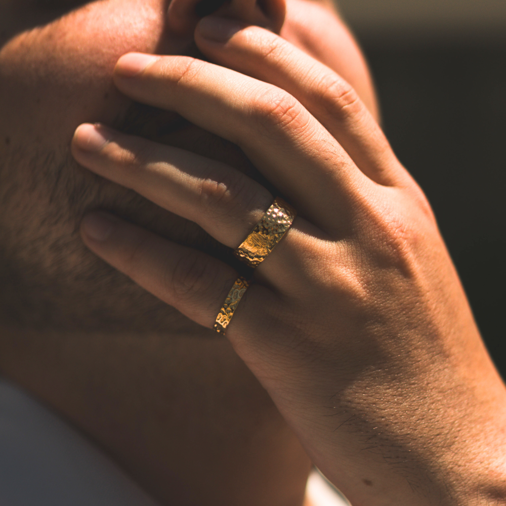 Close-up of a hand wearing two gold rings with a blurred background
