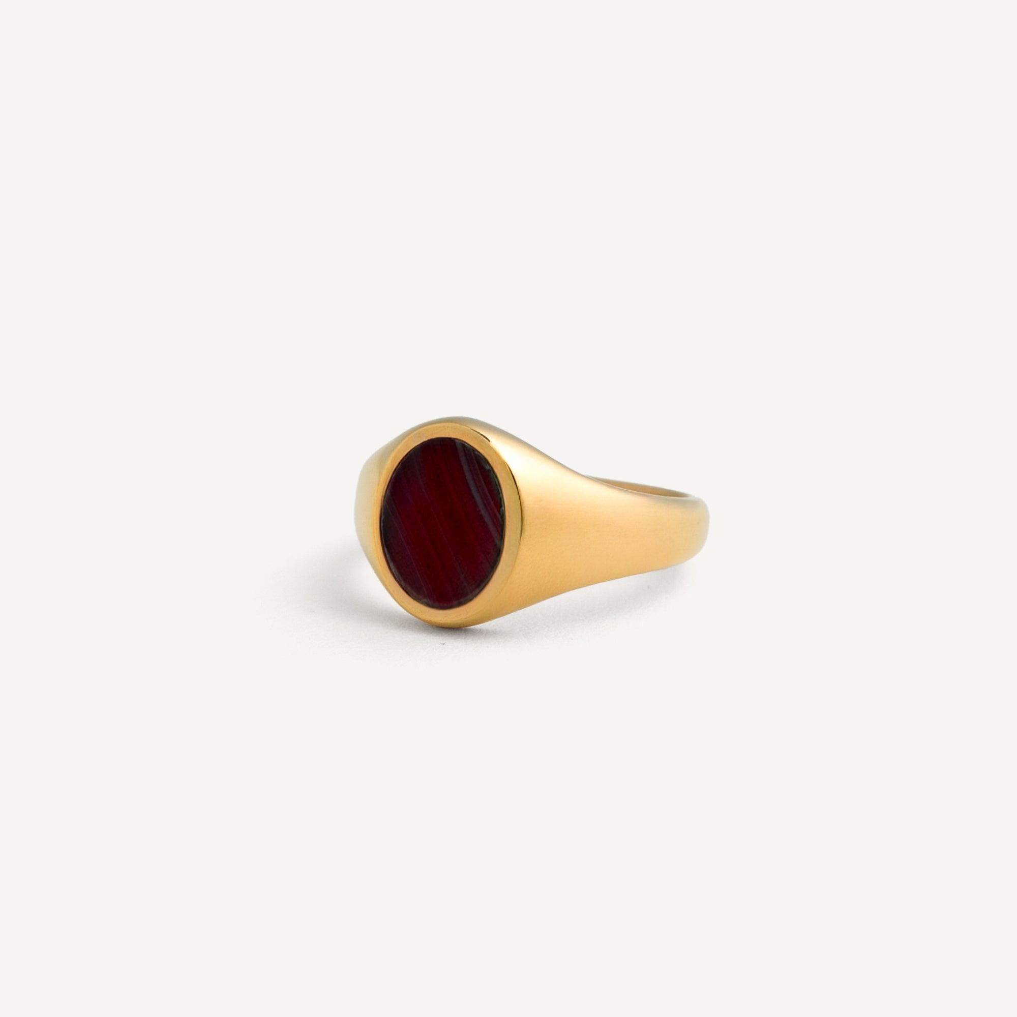 Gold ring with a red stone on a white background