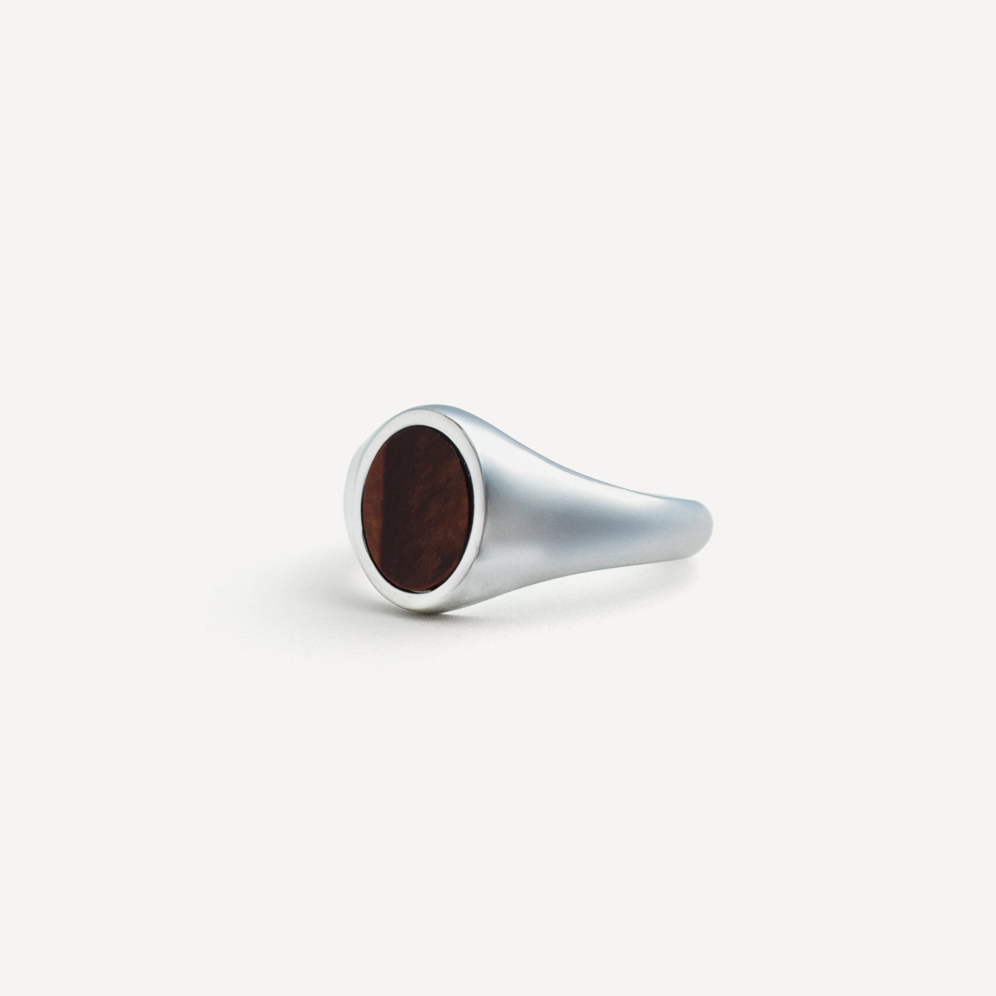 Silver ring with a dark brown wooden inlay on a white background