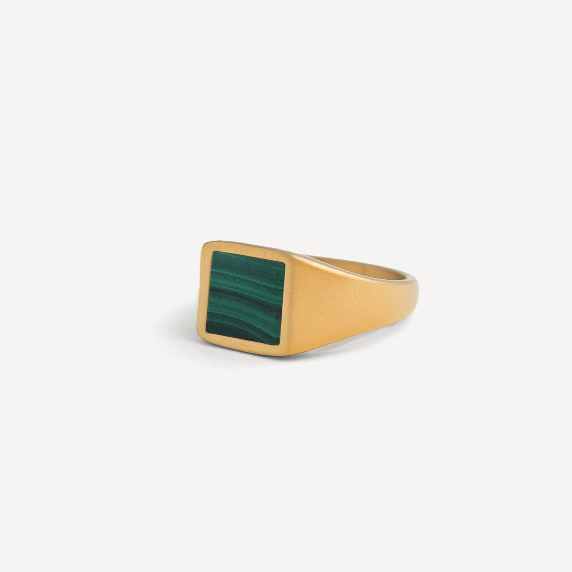 Gold ring with a green stone on a white background