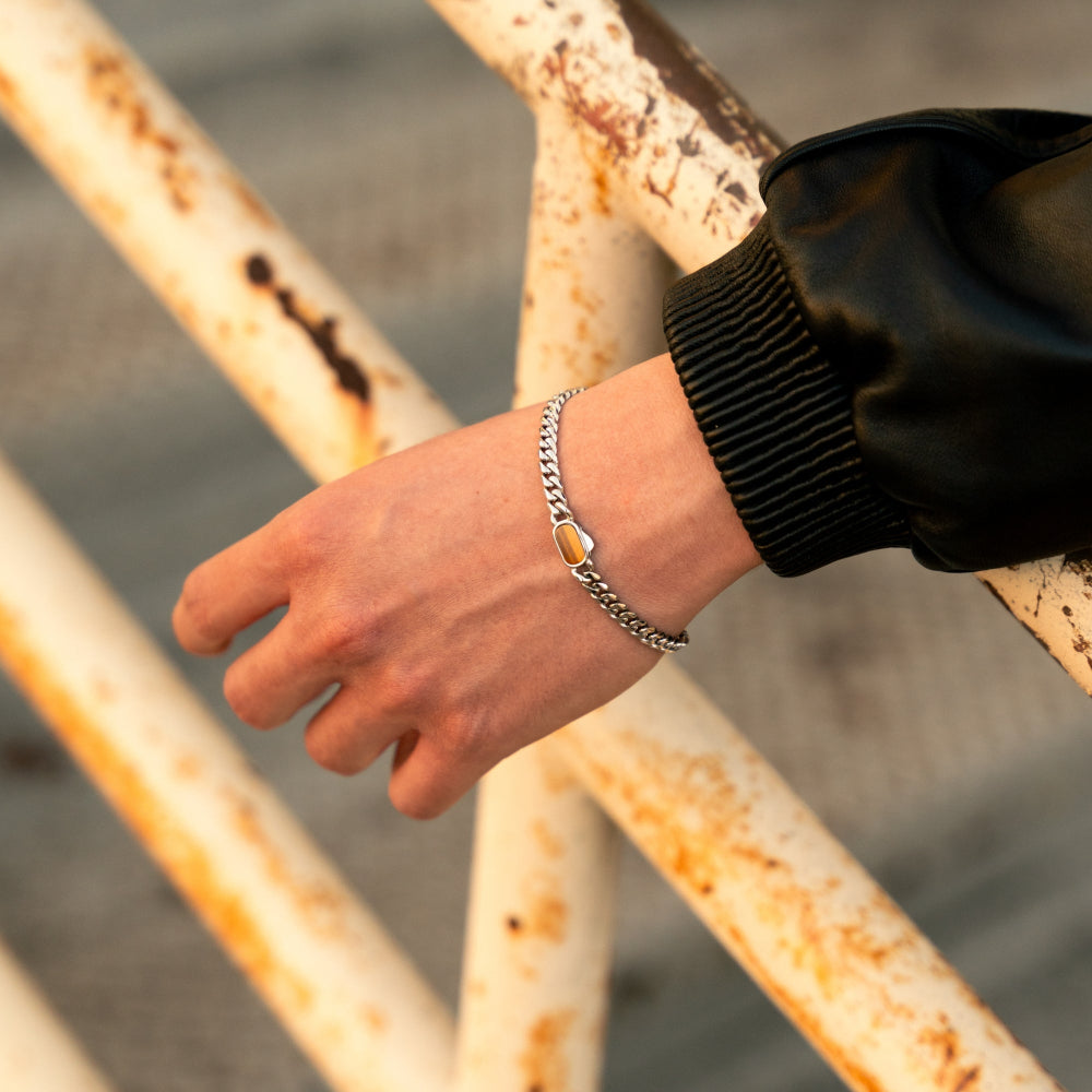 Hand wearing a bracelet on a rusty metal railing with a blurred background