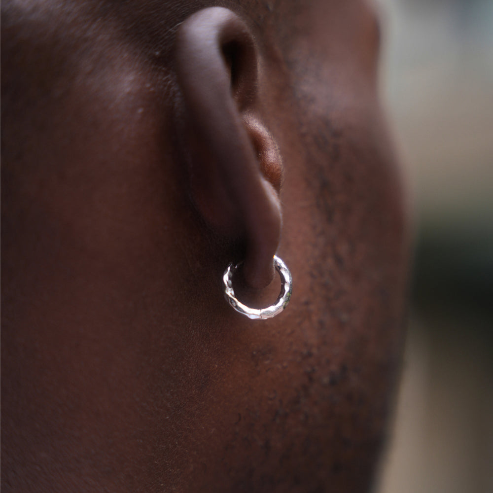 Close-up of an ear with a silver hoop earring on a blurred background