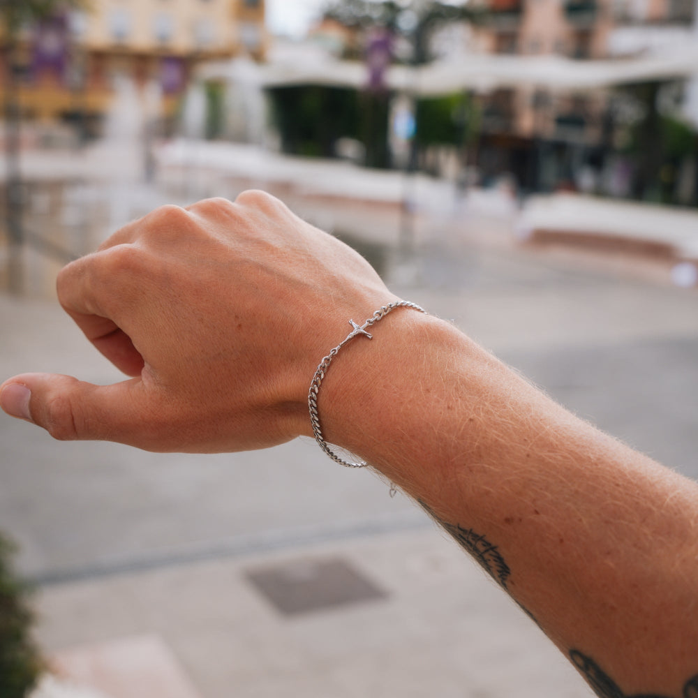 Hand with a bracelet against a blurred outdoor background