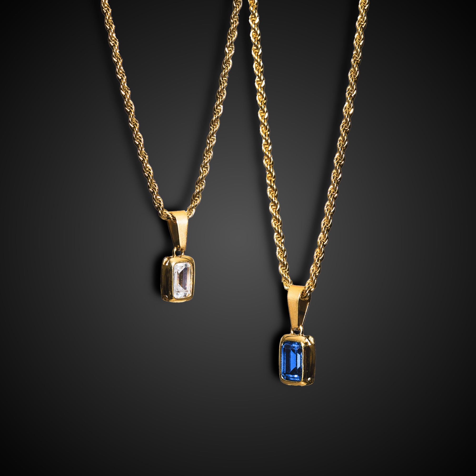 Two gold necklaces with gemstone pendants on a black background