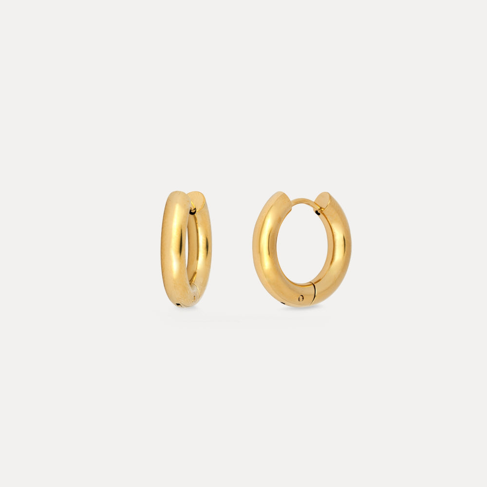 Gold hoop earrings on a light beige background