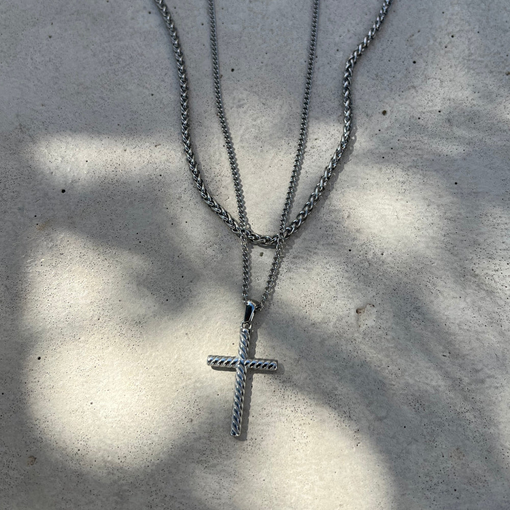 Silver cross necklace on a textured surface