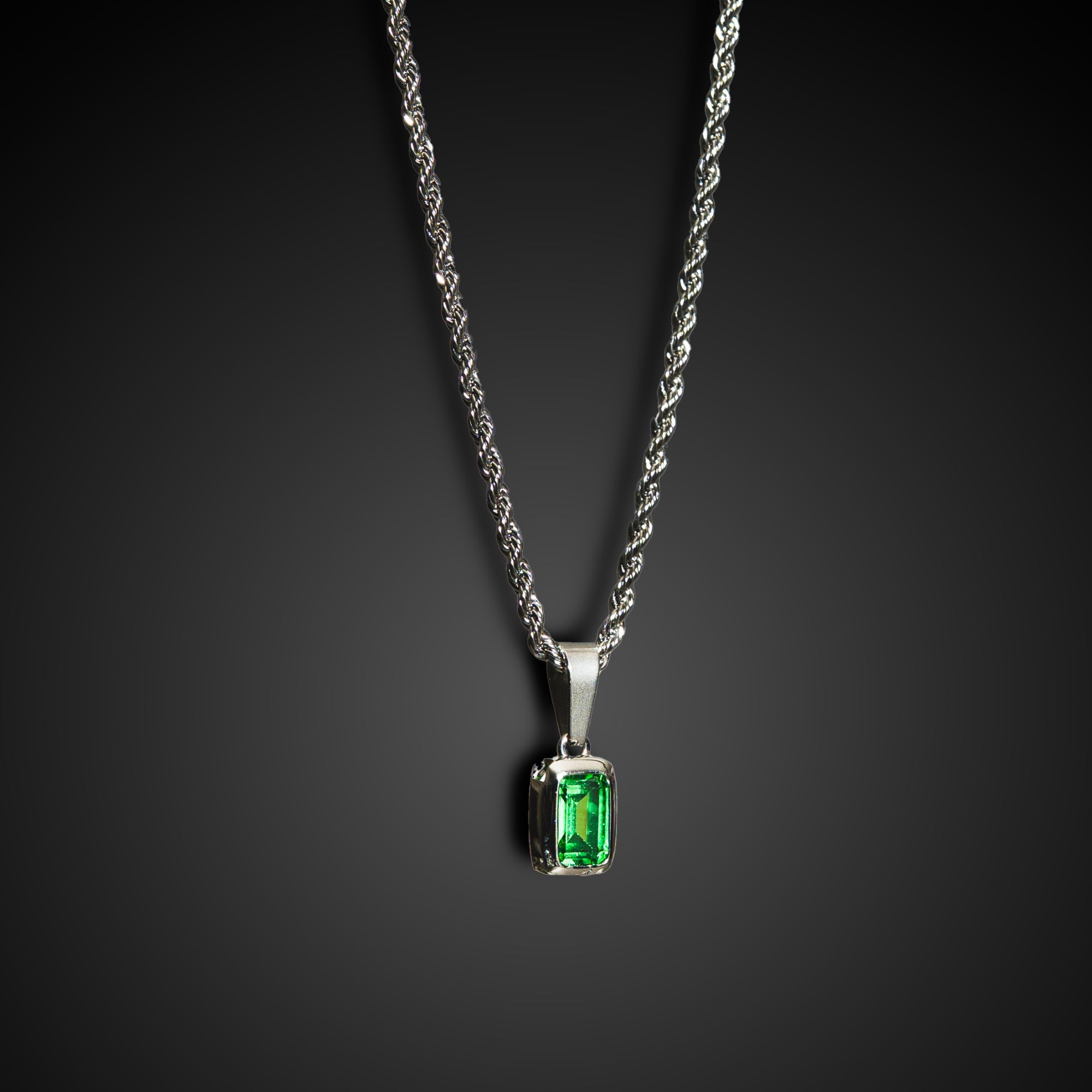 Silver necklace with a green gemstone pendant on a dark background