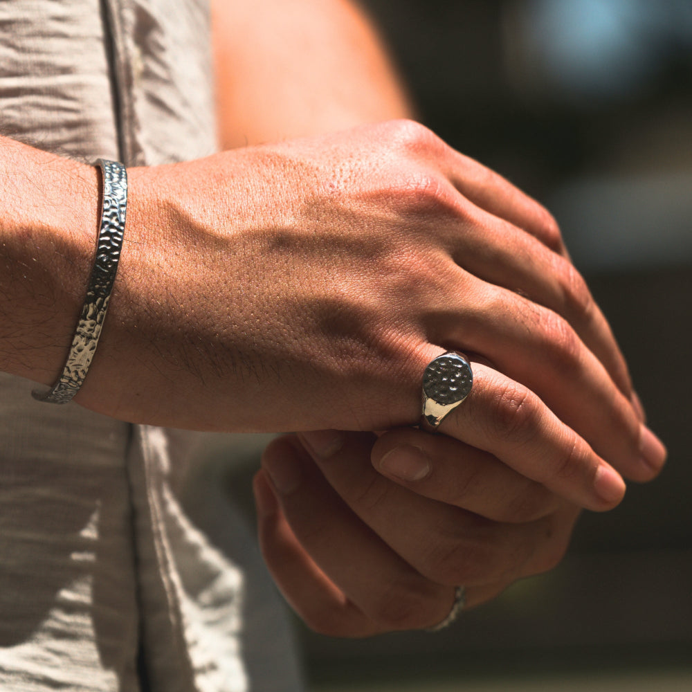 Close-up of a person's hands with a ring and bracelet, blurred background