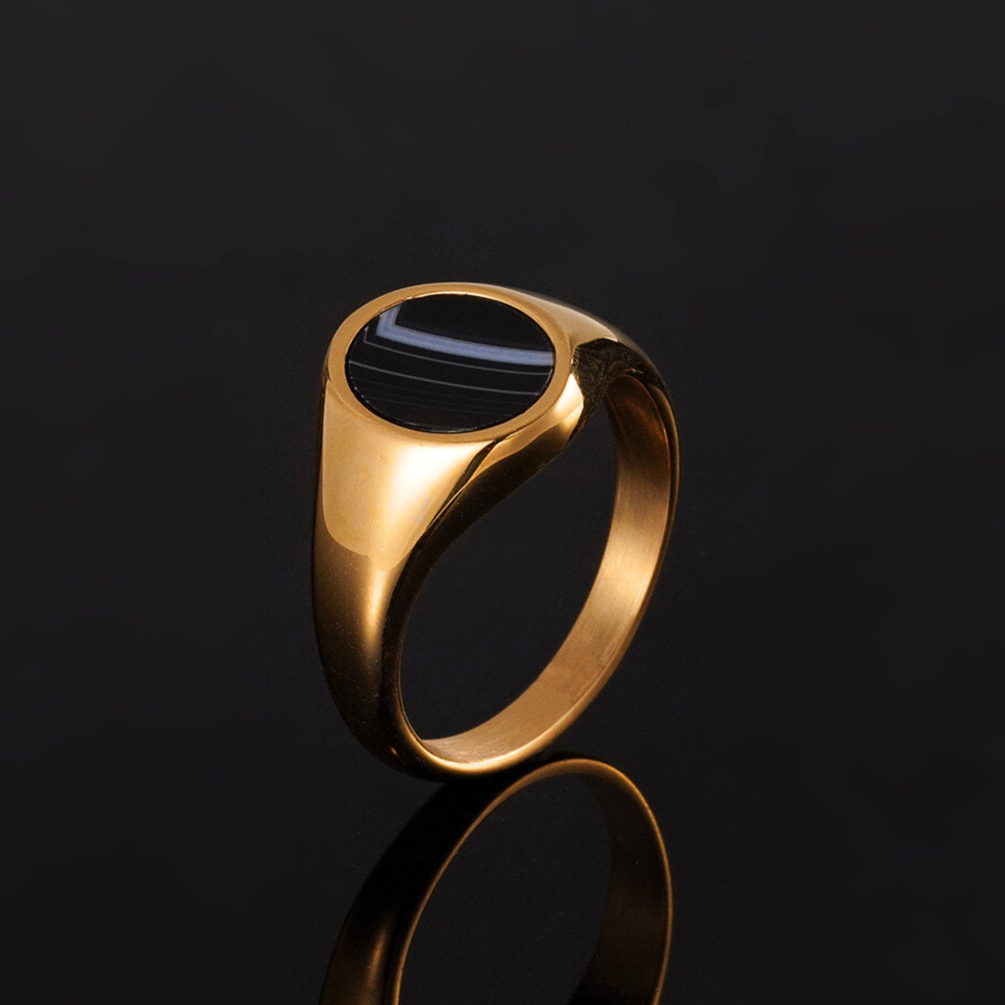Gold ring with a black stone on a black background
