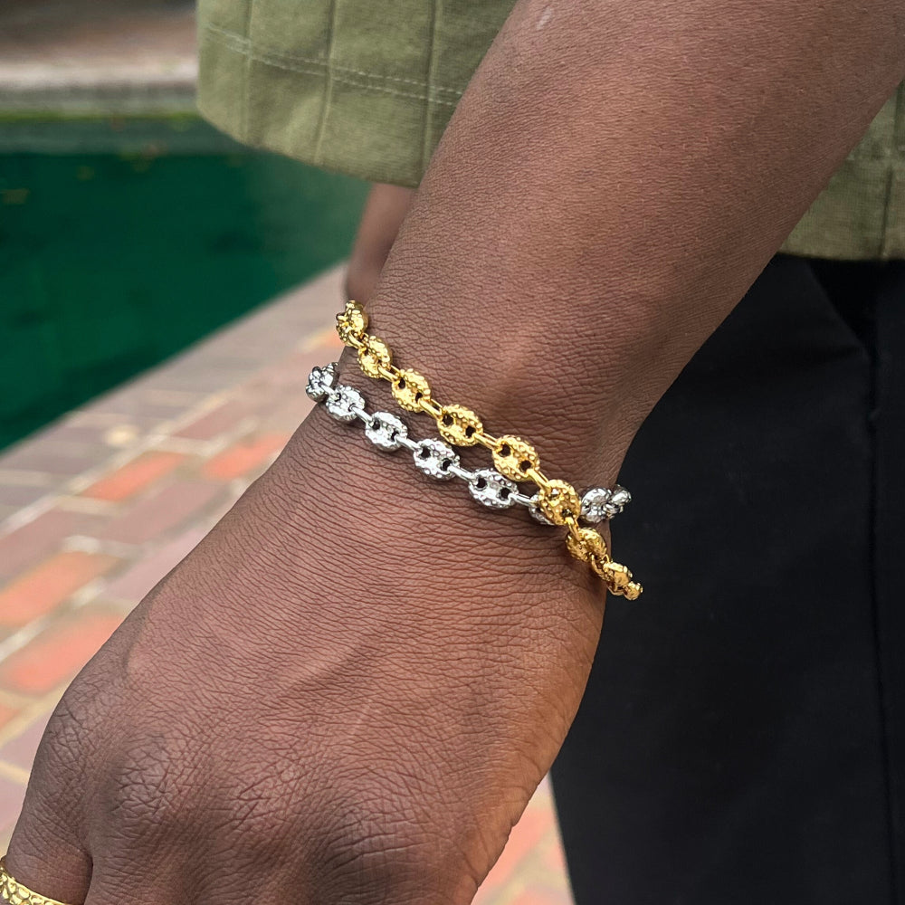 Gold and silver chain bracelet on a wrist with a blurred background
