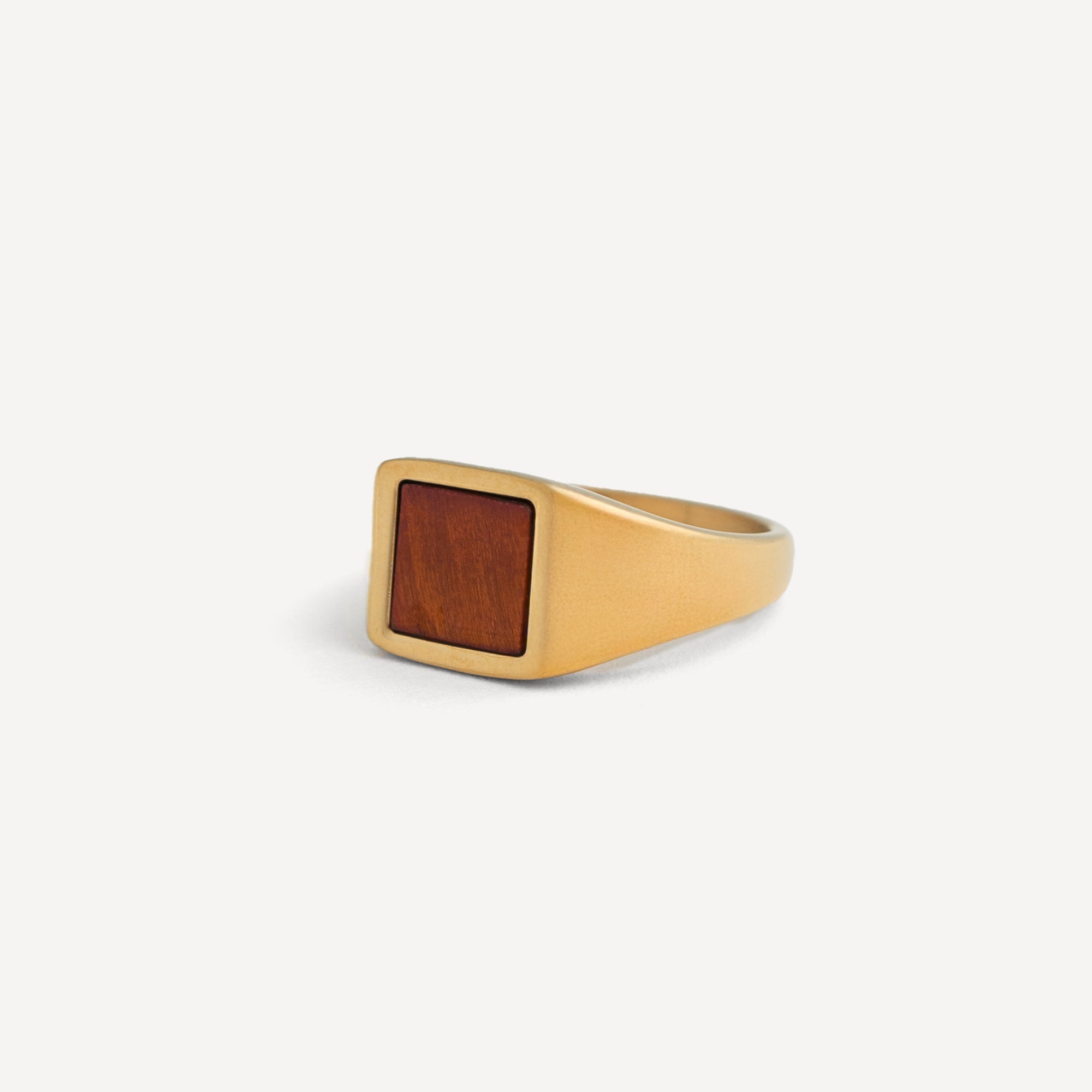 Gold ring with a wooden inlay on a white background