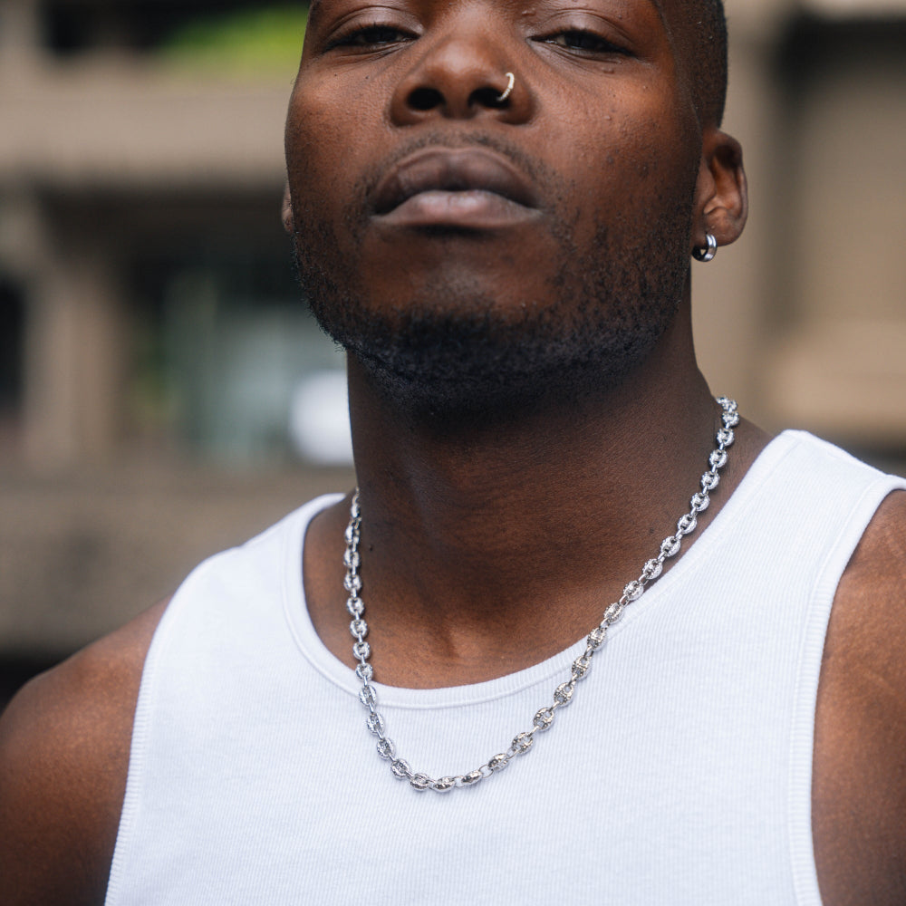 Man wearing a silver chain necklace against a blurred background