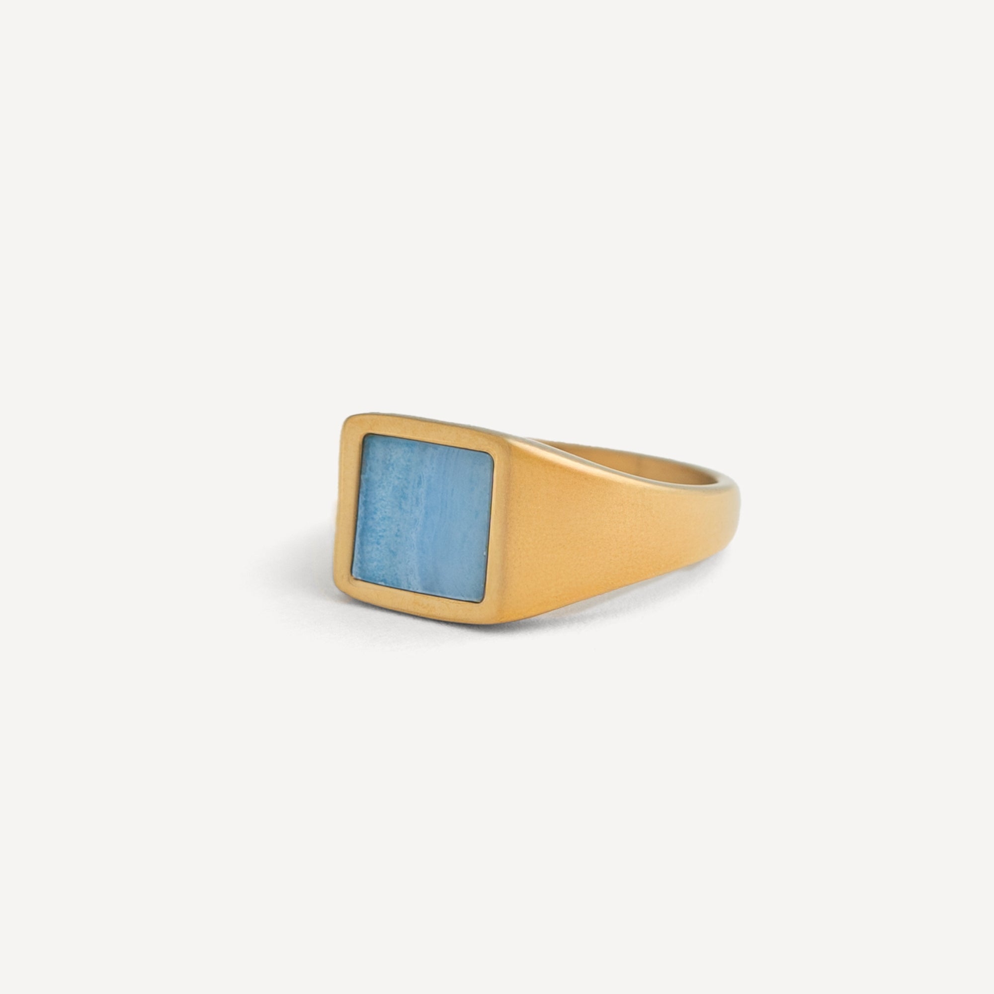 Gold ring with a blue stone on a white background