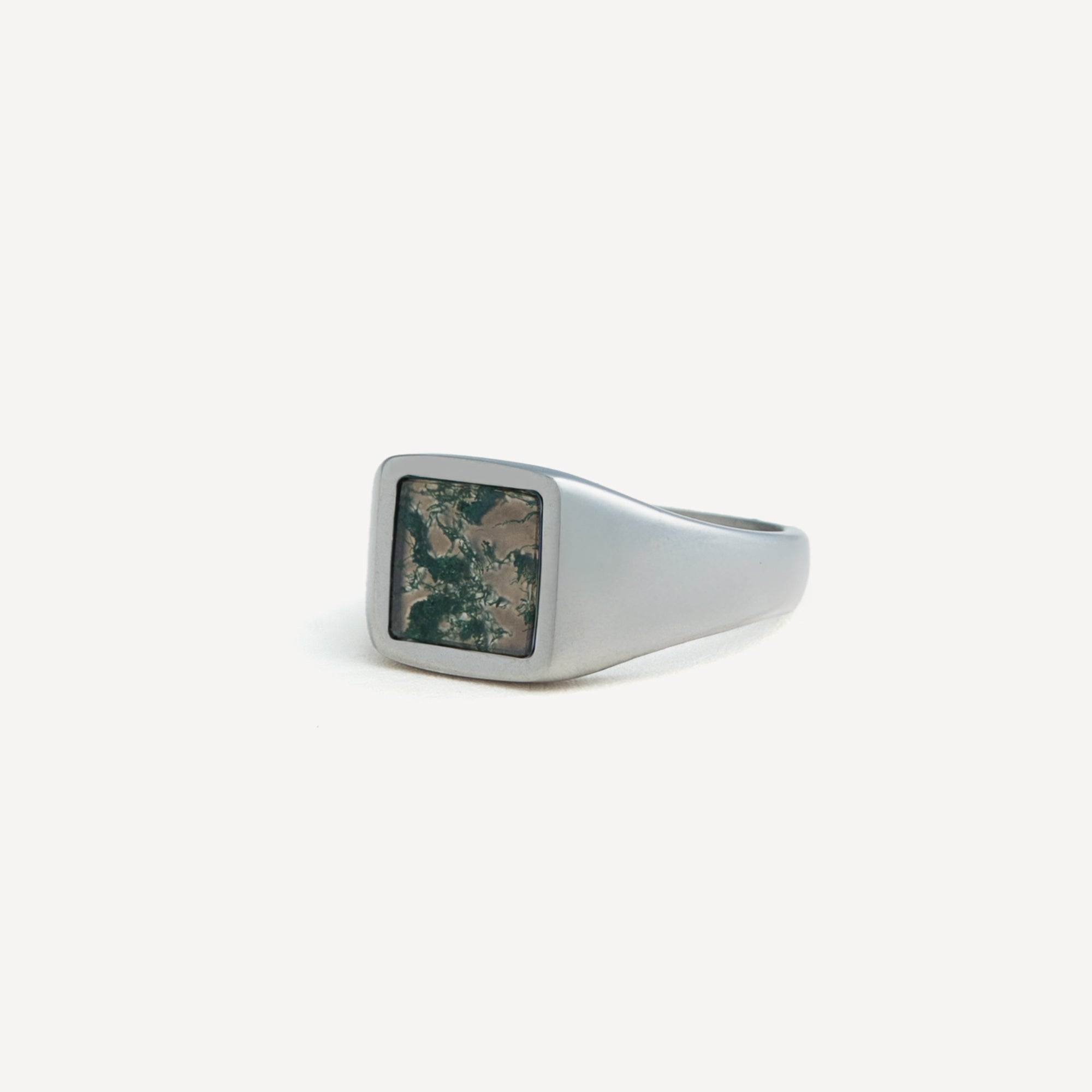 Silver ring with a square stone on a white background