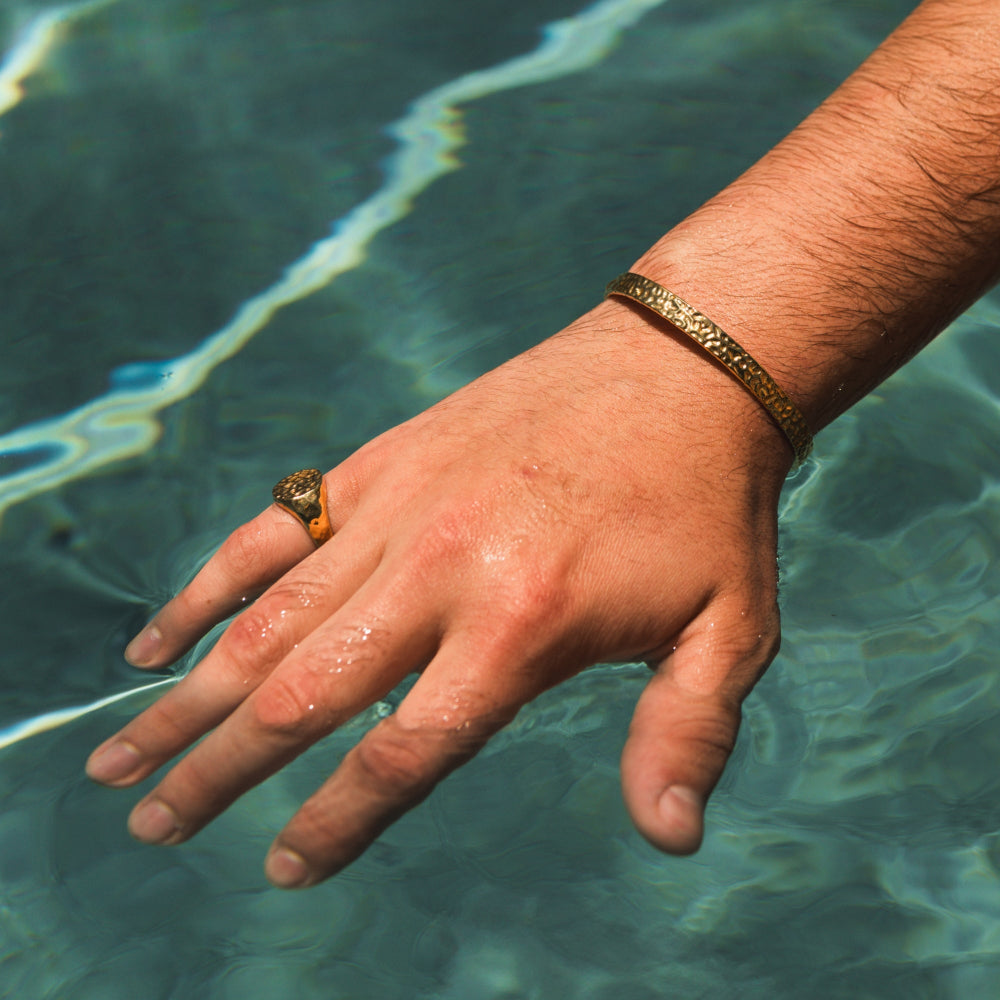 Hand with a ring and bracelet by a pool