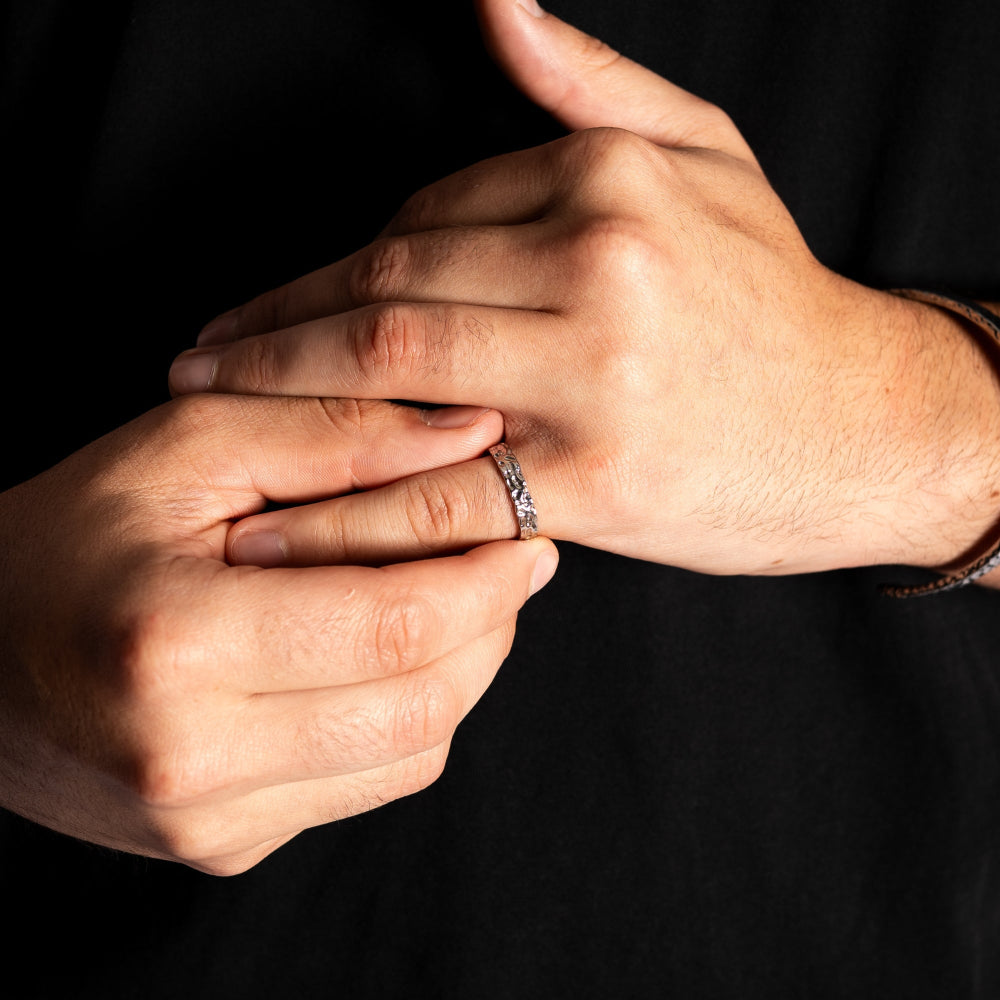 Close-up of two hands with one wearing a ring on a black background