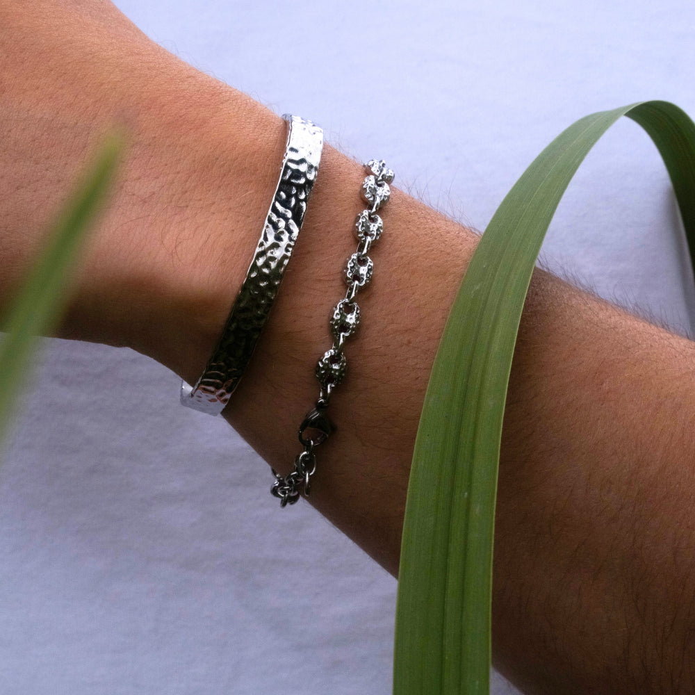 Two silver bracelets on a wrist with a light background