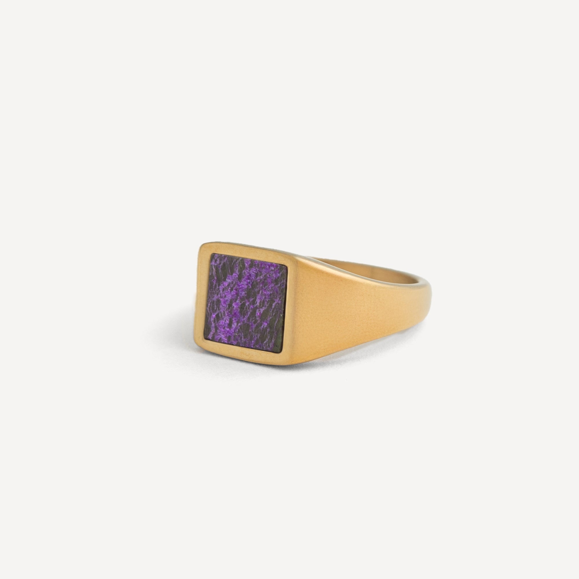 Gold ring with a purple stone on a white background