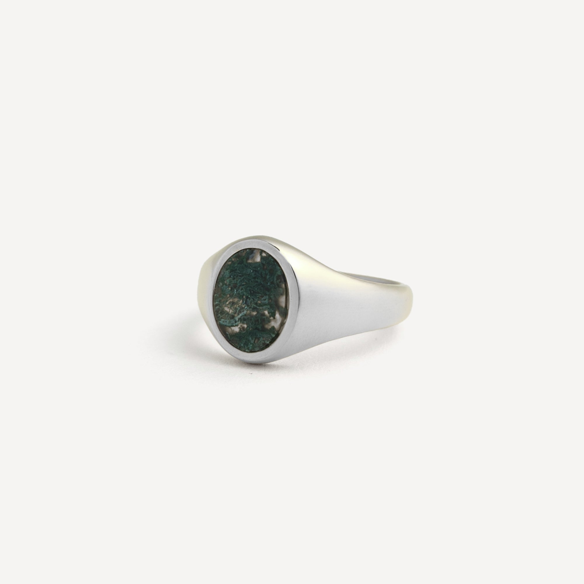 Silver ring with a green stone on a white background