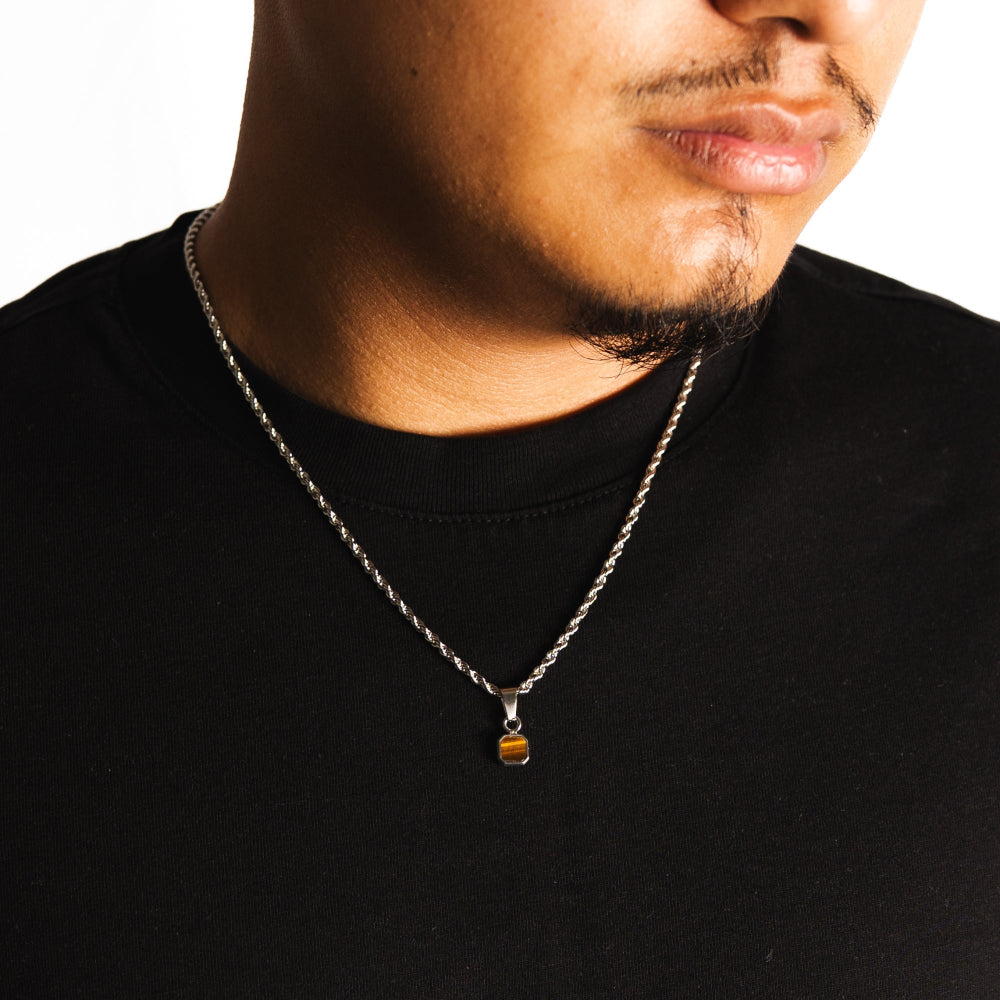Man wearing a black shirt with a necklace featuring a small pendant.