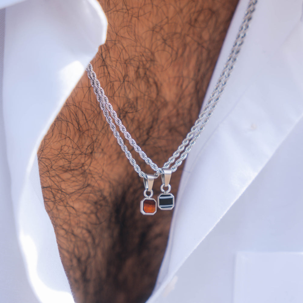 Two silver necklaces with pendant charms on a mannequin bust.