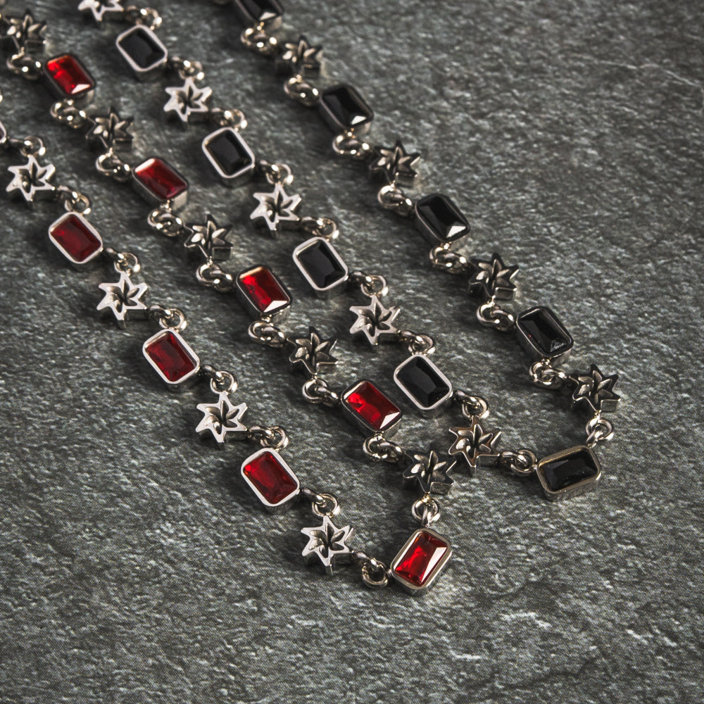 Necklace with red and black gemstones on a gray surface