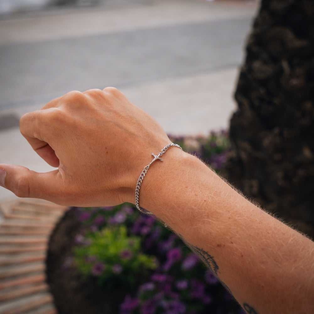 Hand wearing a silver bracelet with a blurred background