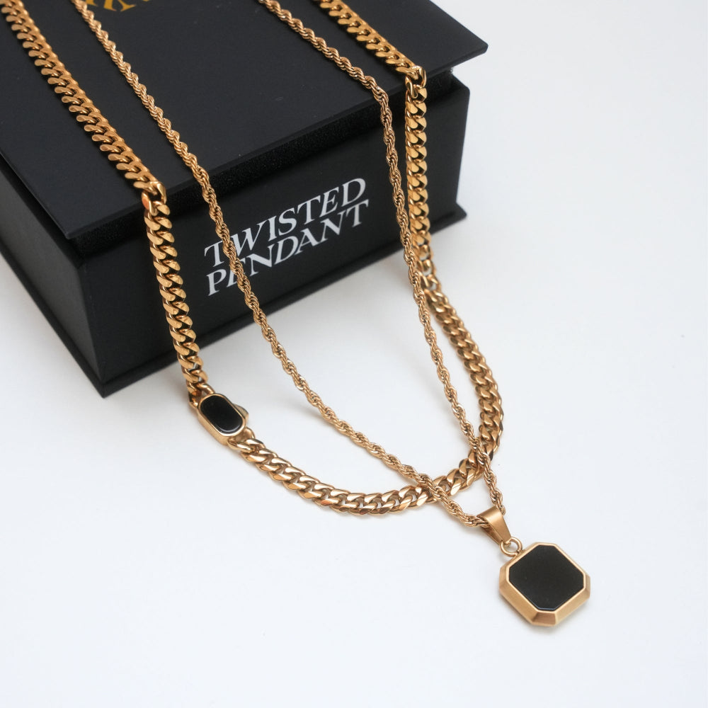 Gold chain necklace with a black pendant on a white background