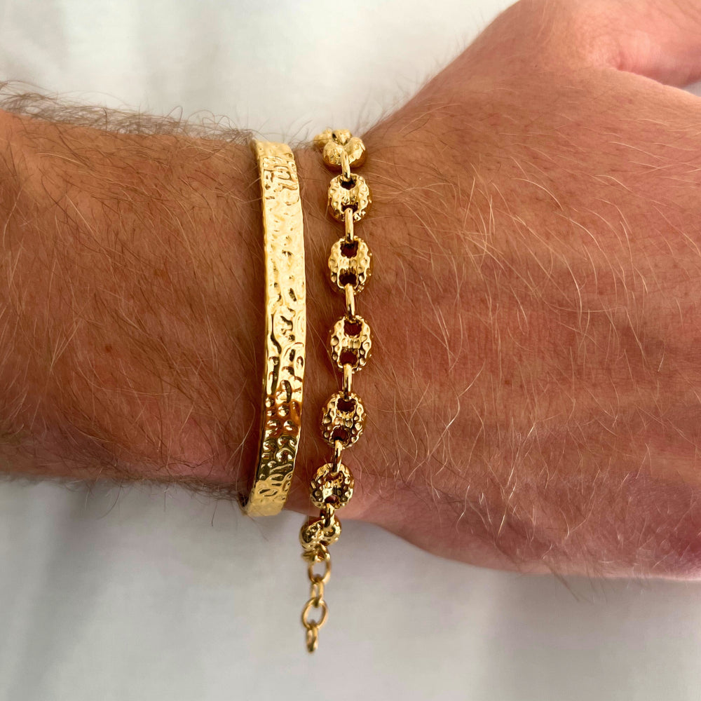 Gold bracelet on a wrist with a plain background