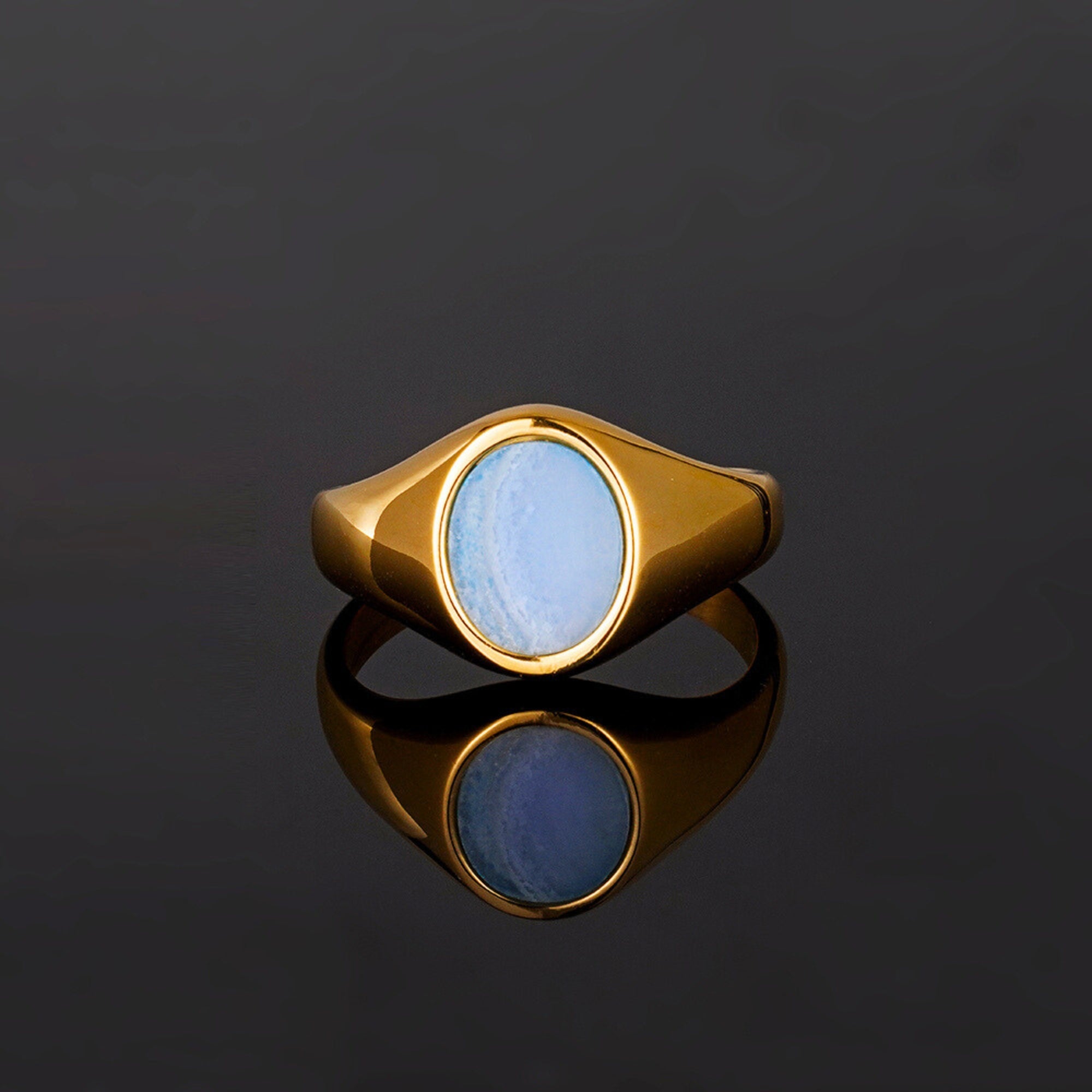 Gold ring with a blue stone on a black background