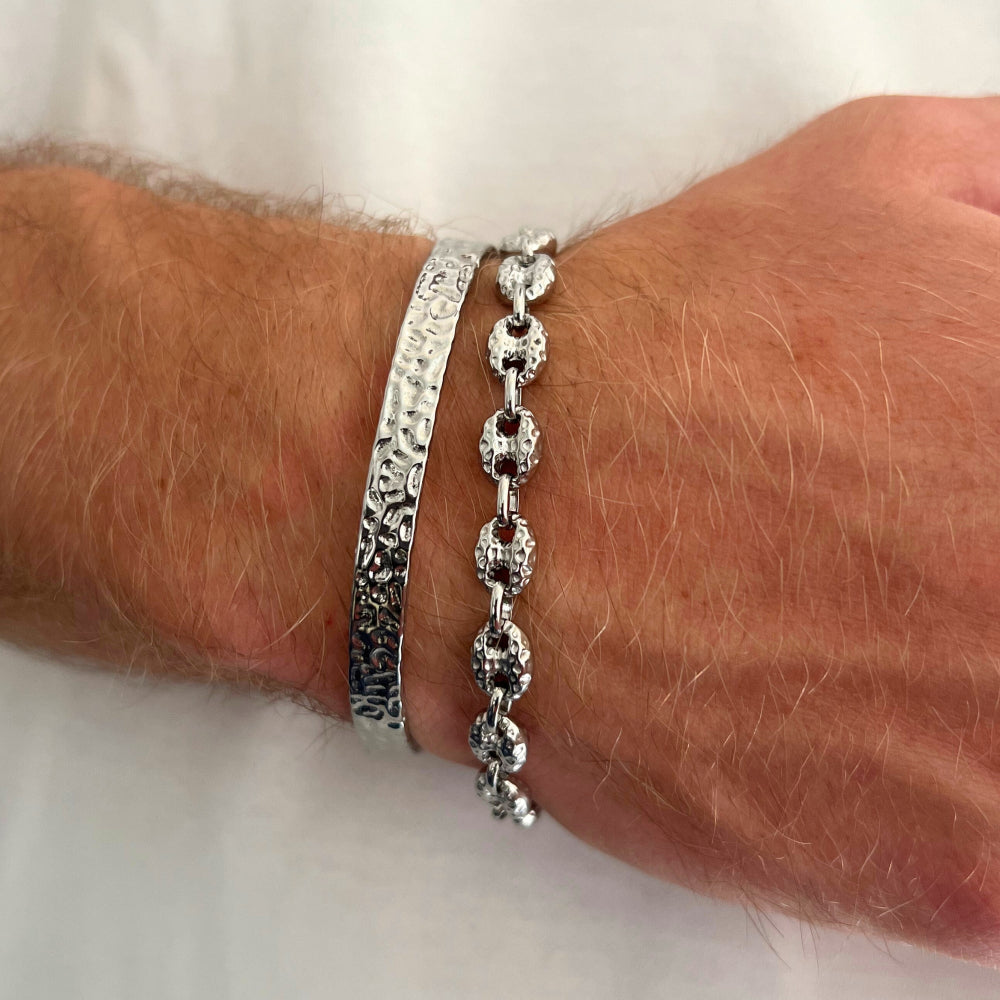 Two silver bracelets on a wrist against a white background