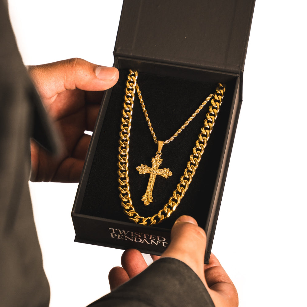 Gold chain with cross pendant in a black jewelry box held by a person.
