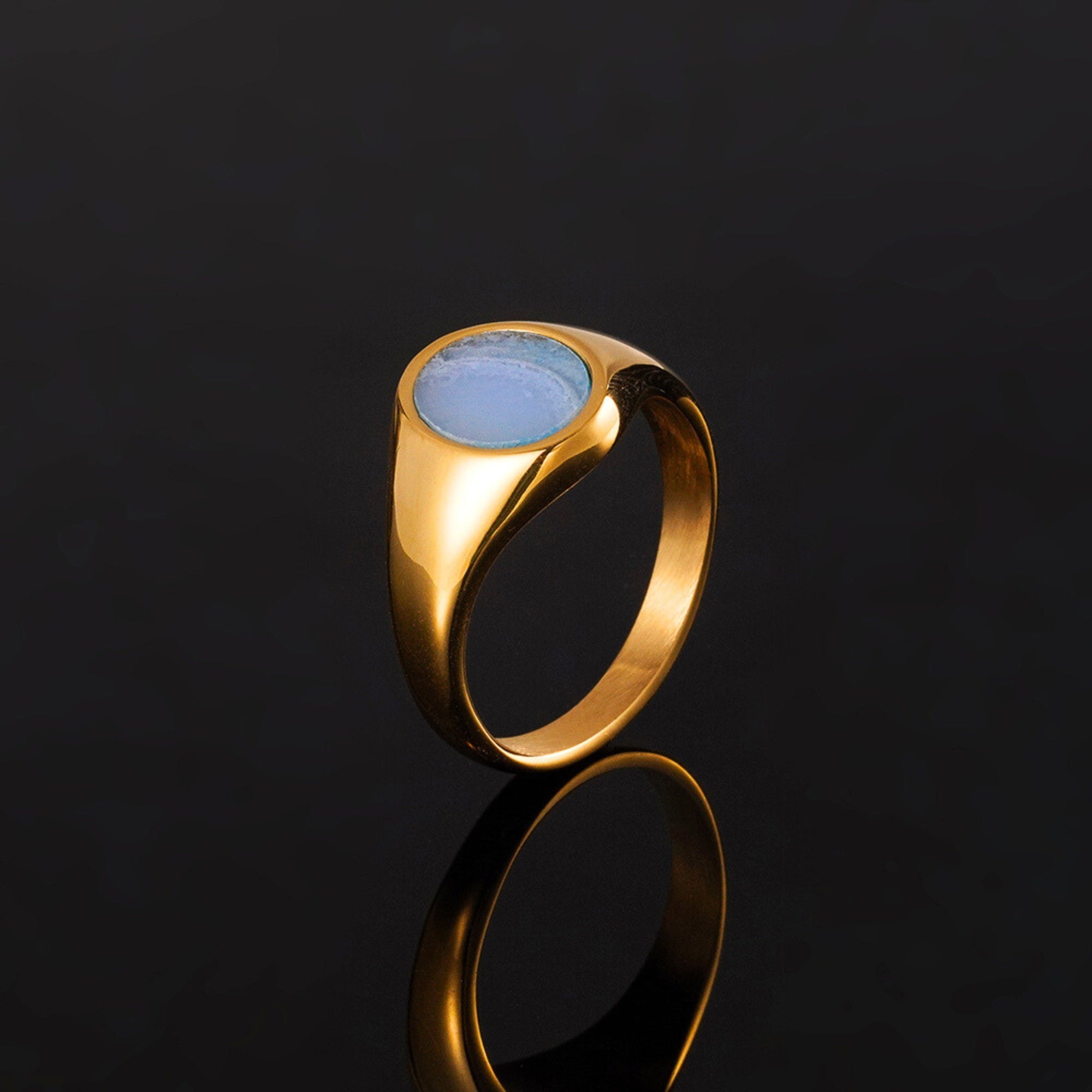 Gold ring with a blue stone on a black background