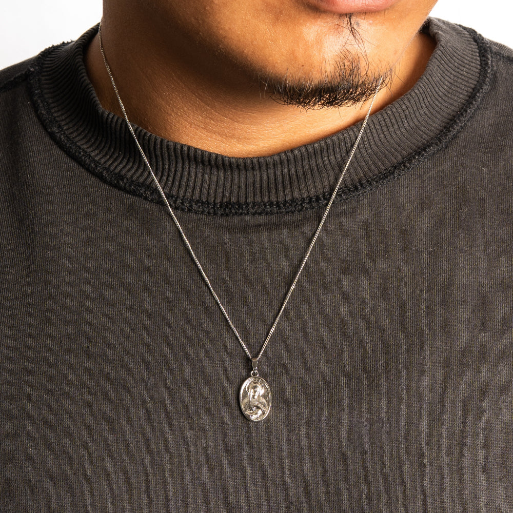 Person wearing a dark gray sweater with a necklace featuring a pendant.