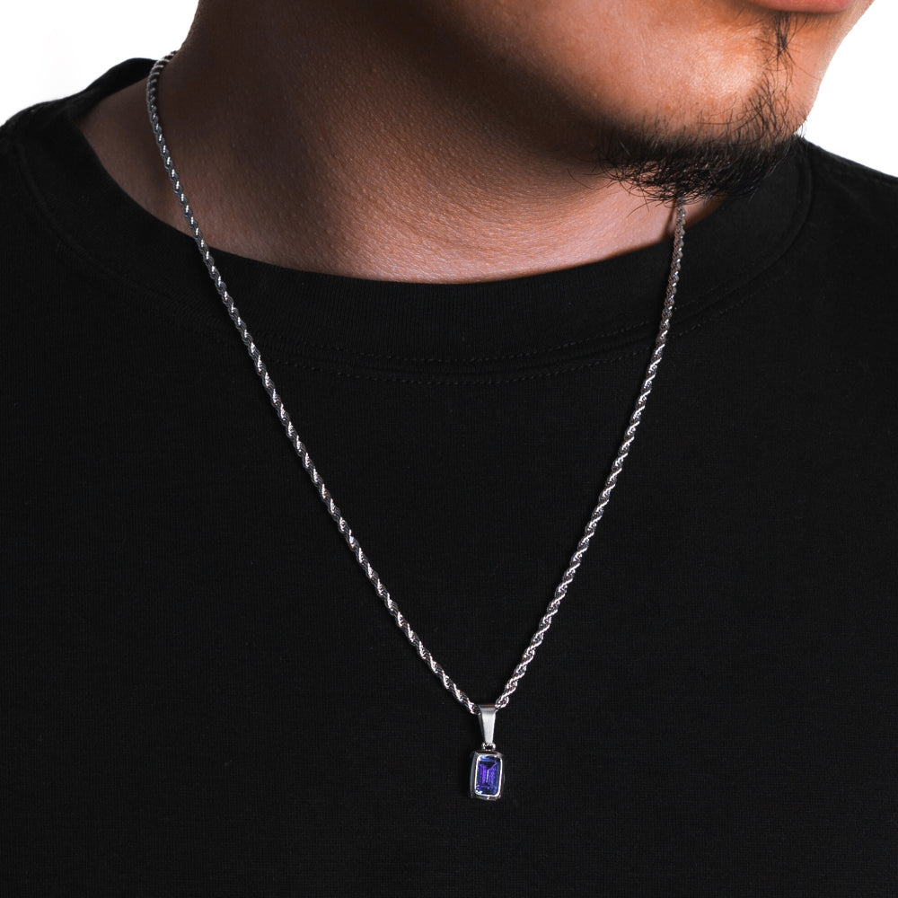 Silver necklace with a purple pendant worn by a person on a black background