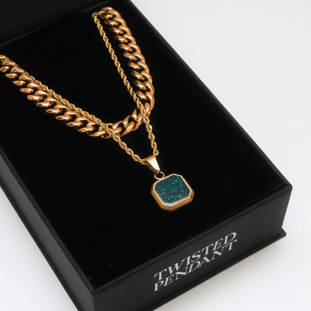 Gold chain necklace with a green pendant on a black box labeled 'Twisted Pendant'.
