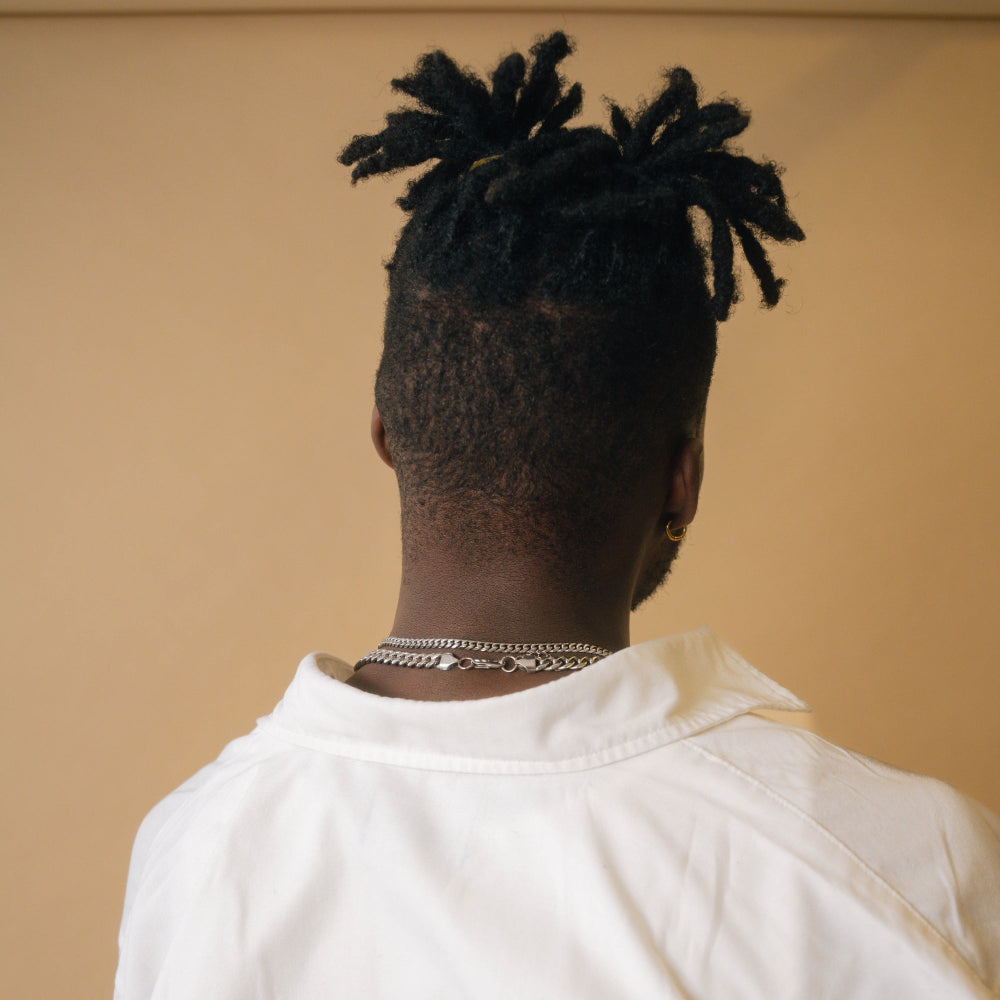 Person with styled hair from behind wearing a white shirt against a beige background
