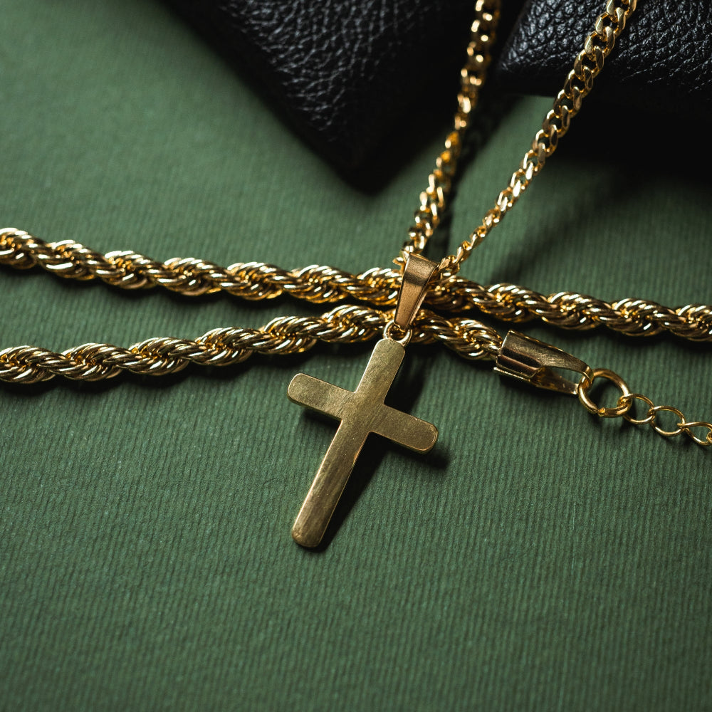 Gold chain with a cross pendant on a green surface
