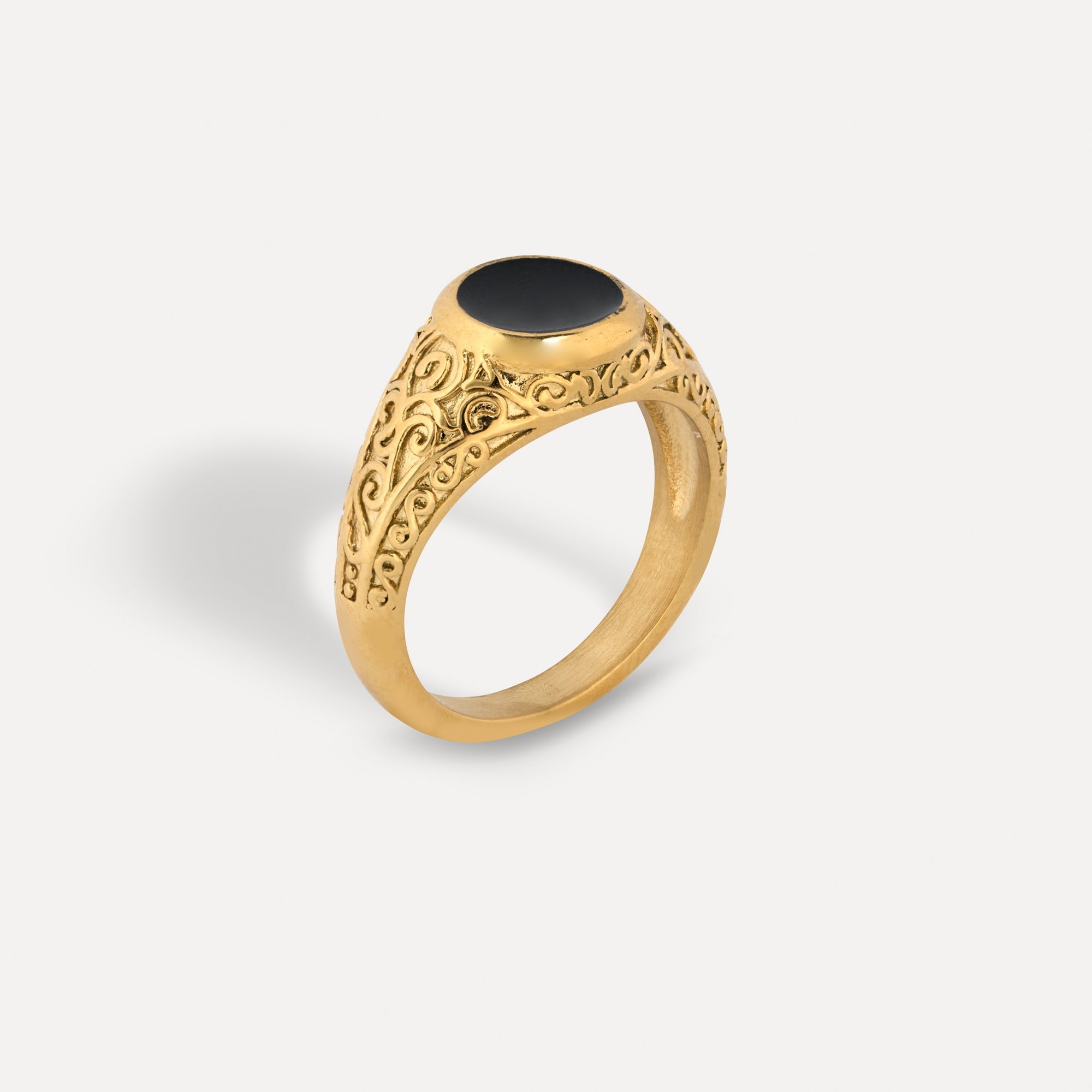 Gold ring with black stone on a light gray background