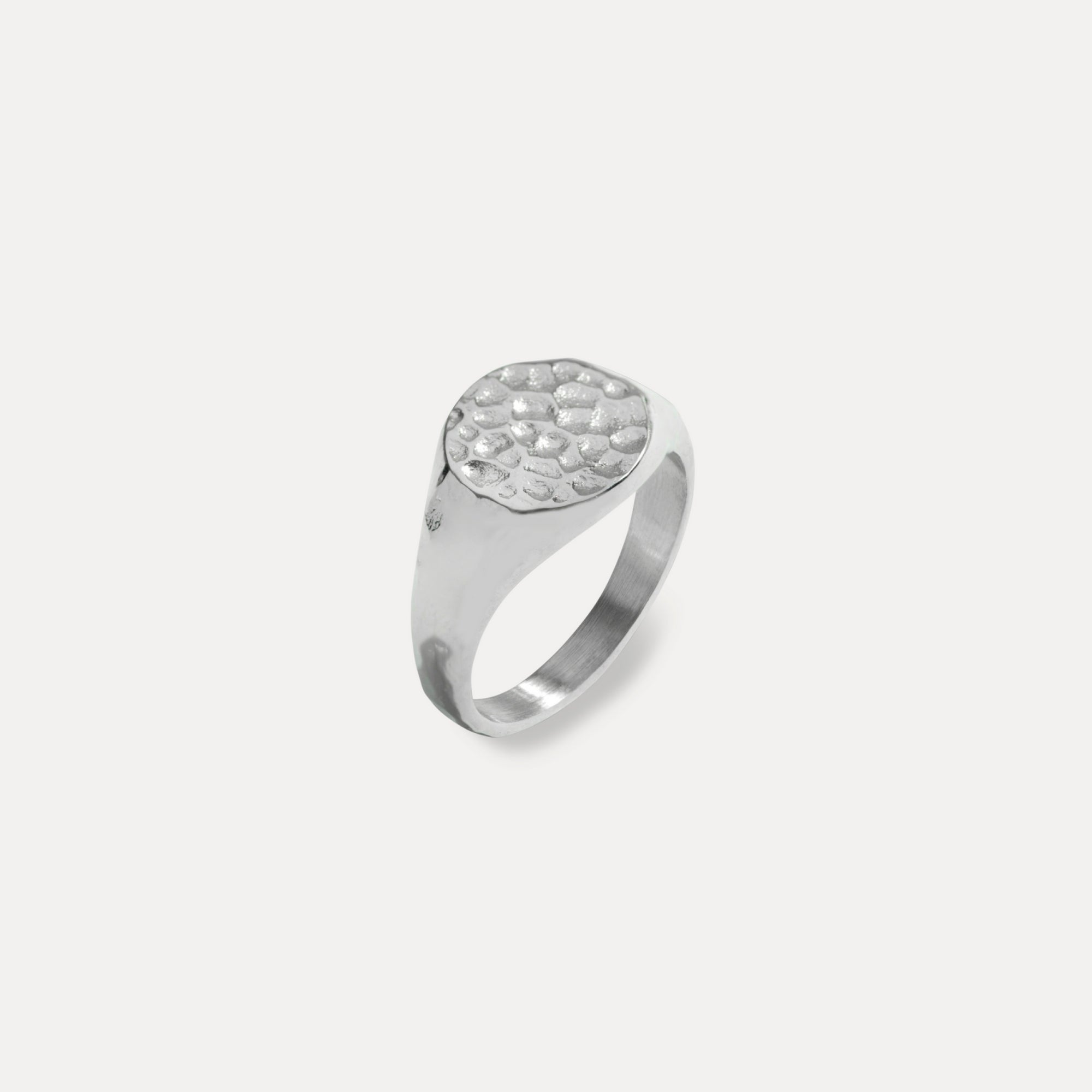 Silver ring with textured design on a light gray background