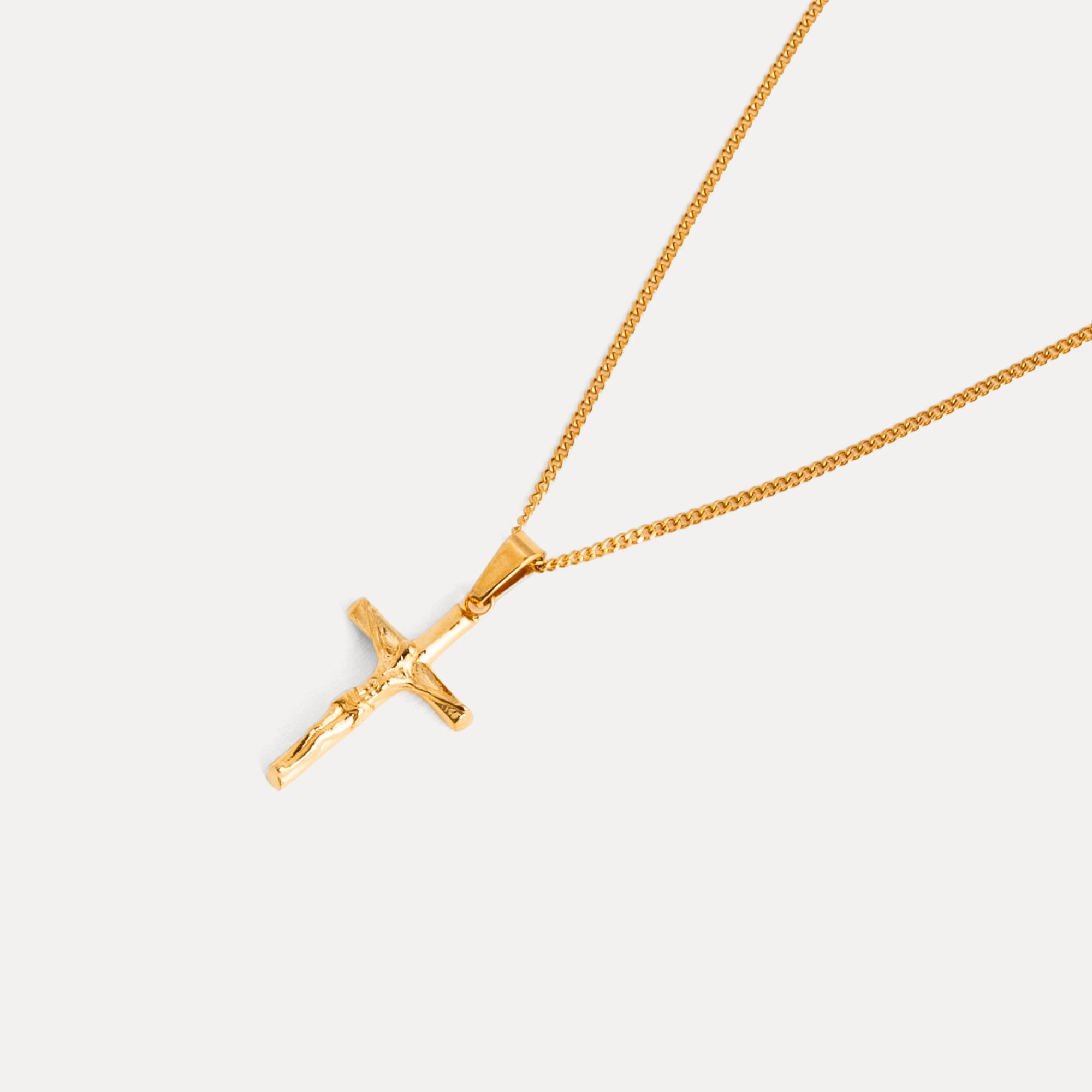 Gold cross necklace on a light gray background