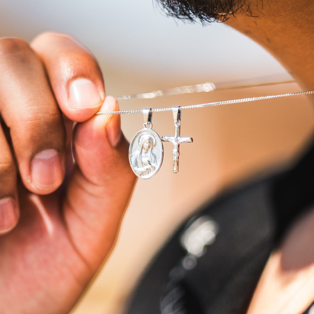Close-up of a hand holding a silver necklace with two pendants.