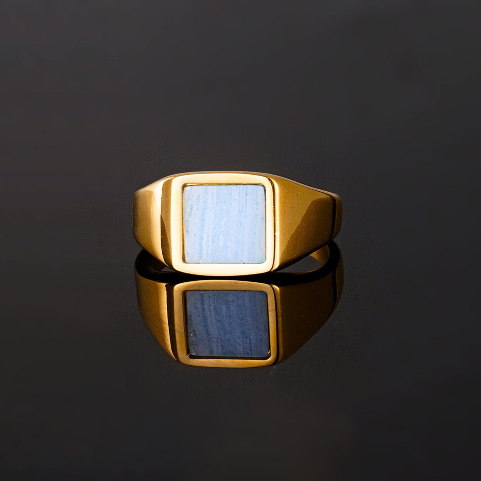 Gold ring with a blue stone on a black background