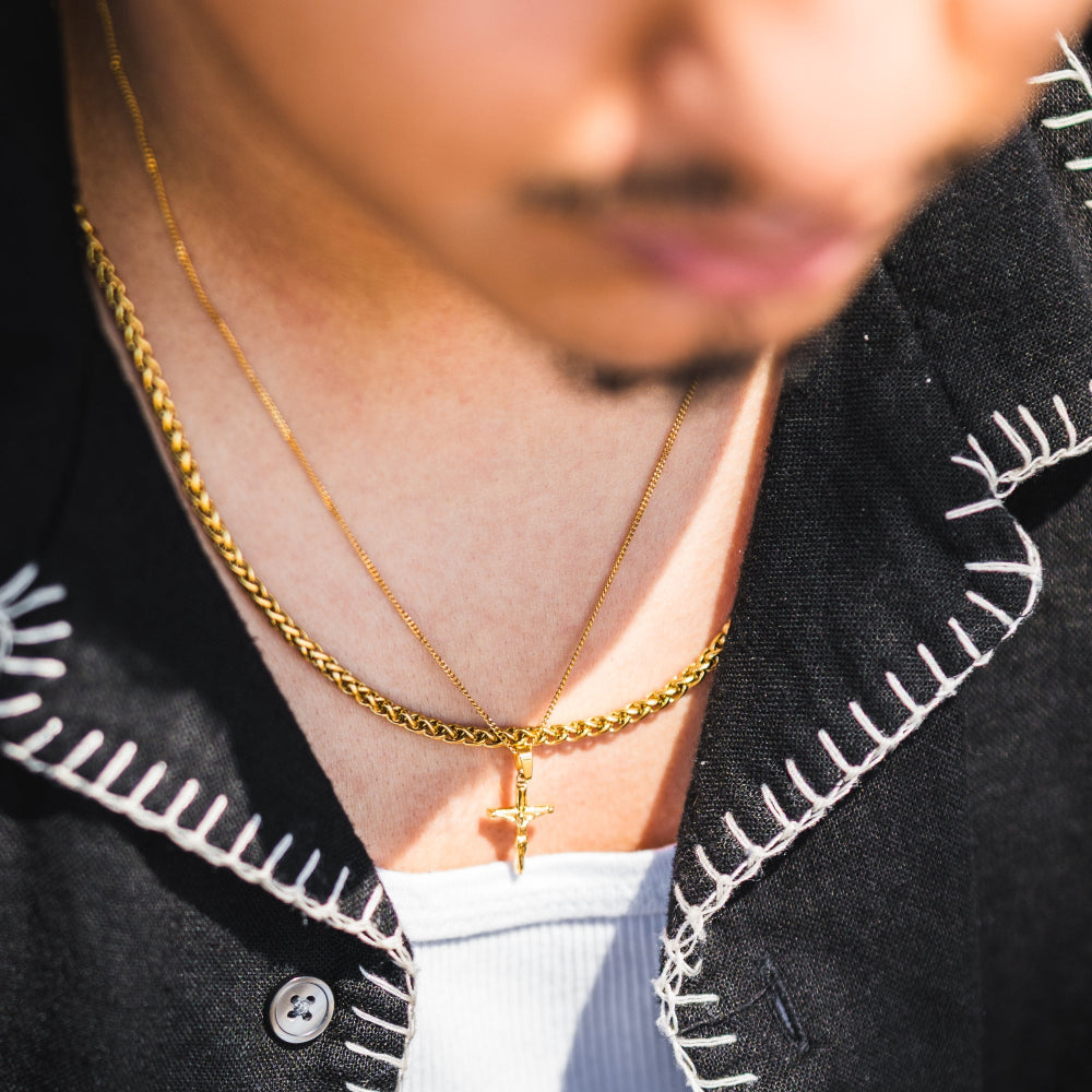 Person wearing two gold necklaces with a blurred background