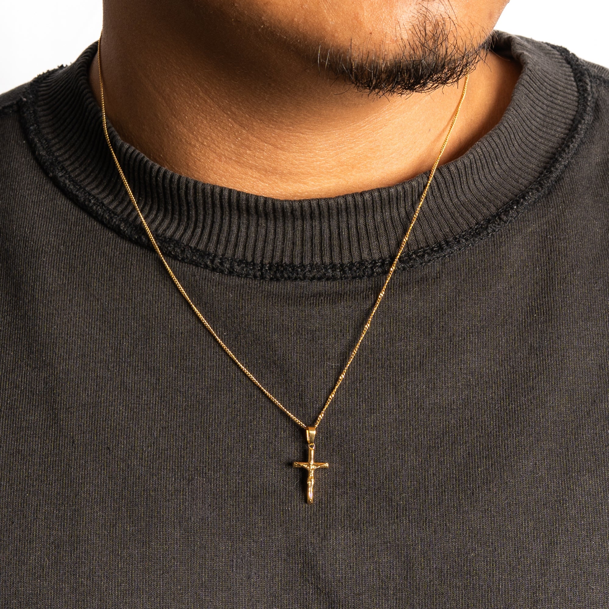 Gold cross necklace on a person wearing a black sweater
