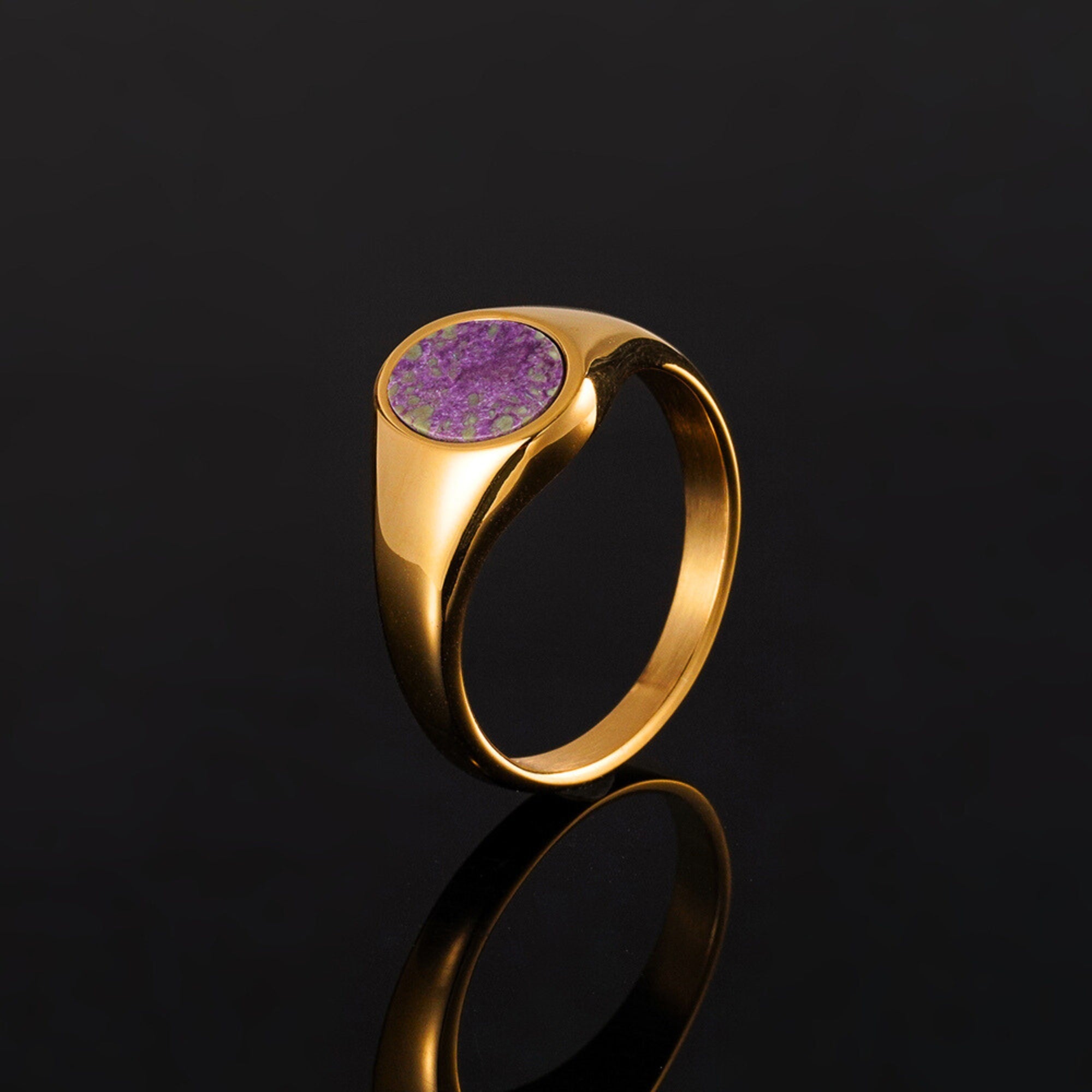 Gold ring with a purple stone on a black background