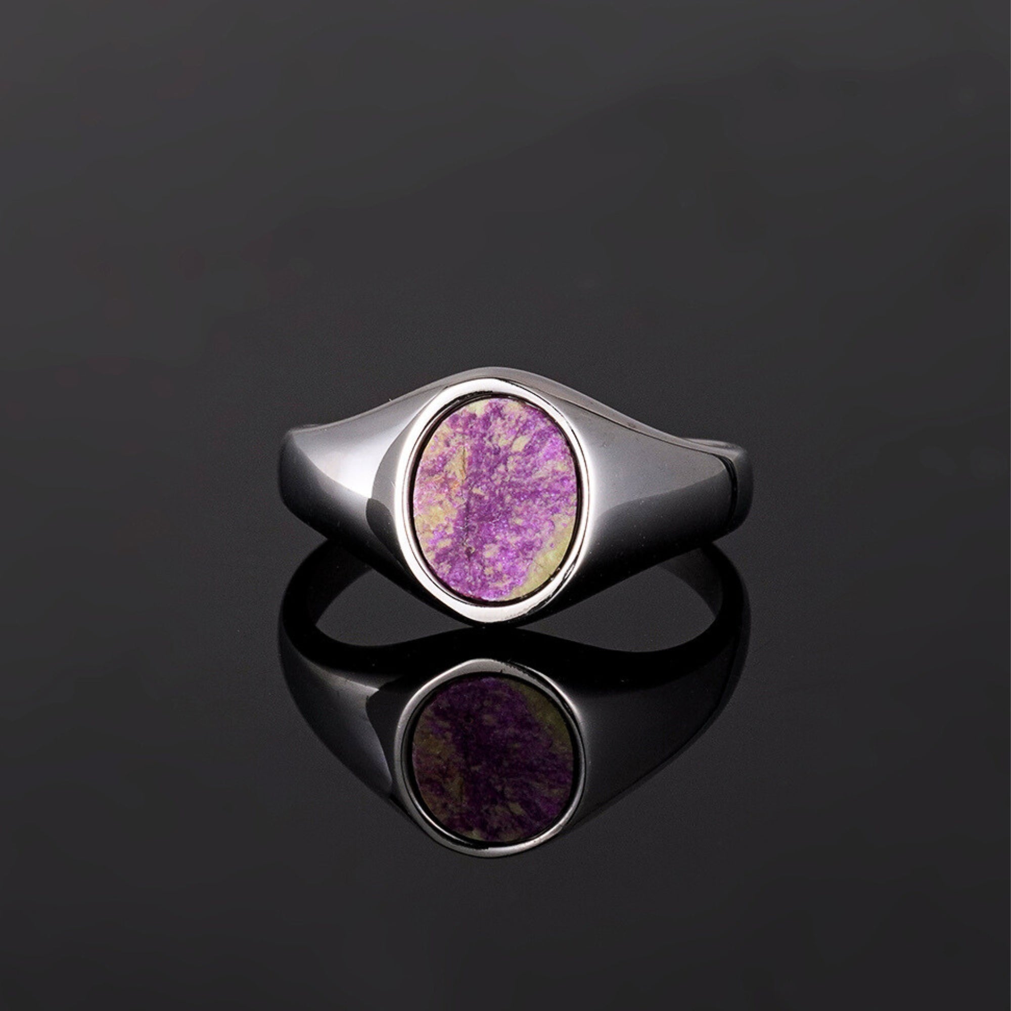 Silver ring with a purple stone on a black background
