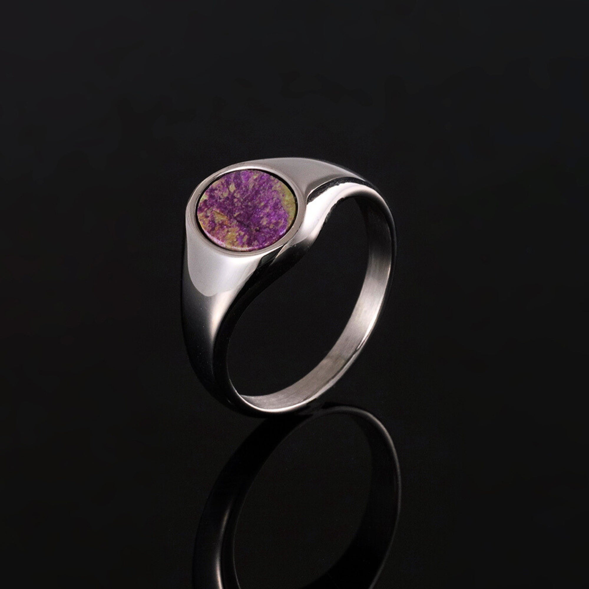 Silver ring with a purple stone on a black background