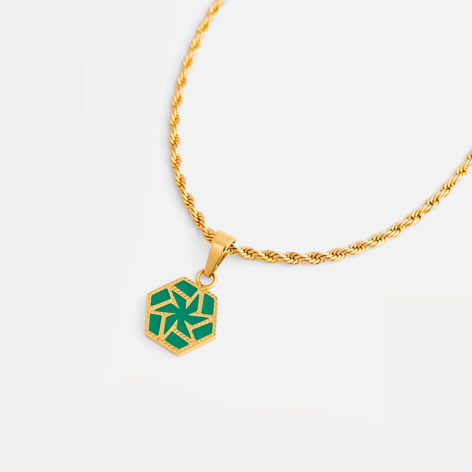 Gold necklace with a green hexagonal pendant on a white background